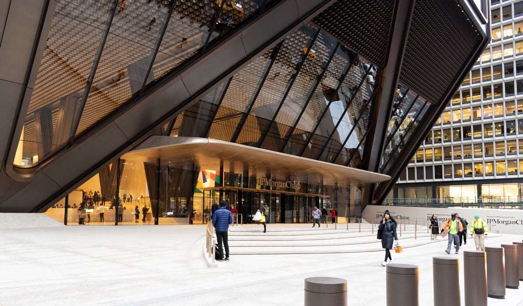 People walking outside the JPMorgan Chase building with modern glass facade and steps leading to the entrance.