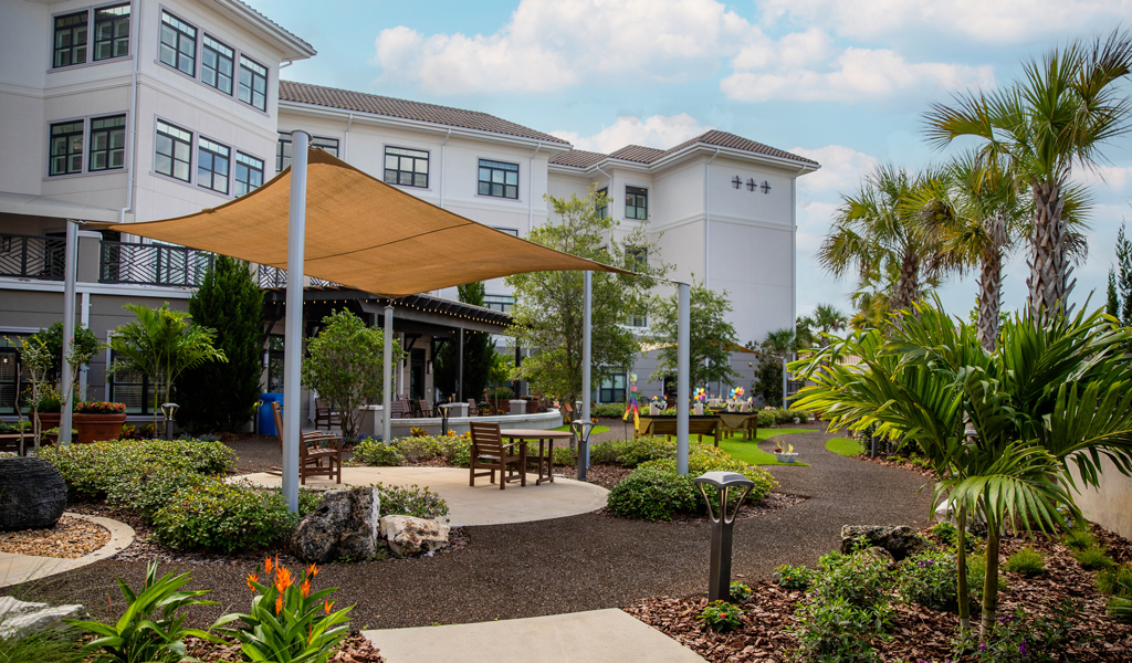 Mayflower Memory Care Garden featuring walkways, seating areas and gardens in front of a 3-story senior living residence.