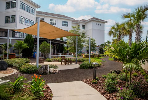 Mayflower Memory Care Garden featuring walkways, seating areas and gardens in front of a 3-story senior living residence.