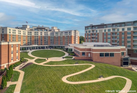 Aerial view of the Westminster at Canterbury campus with brick buildings and green open space set against a blue sky