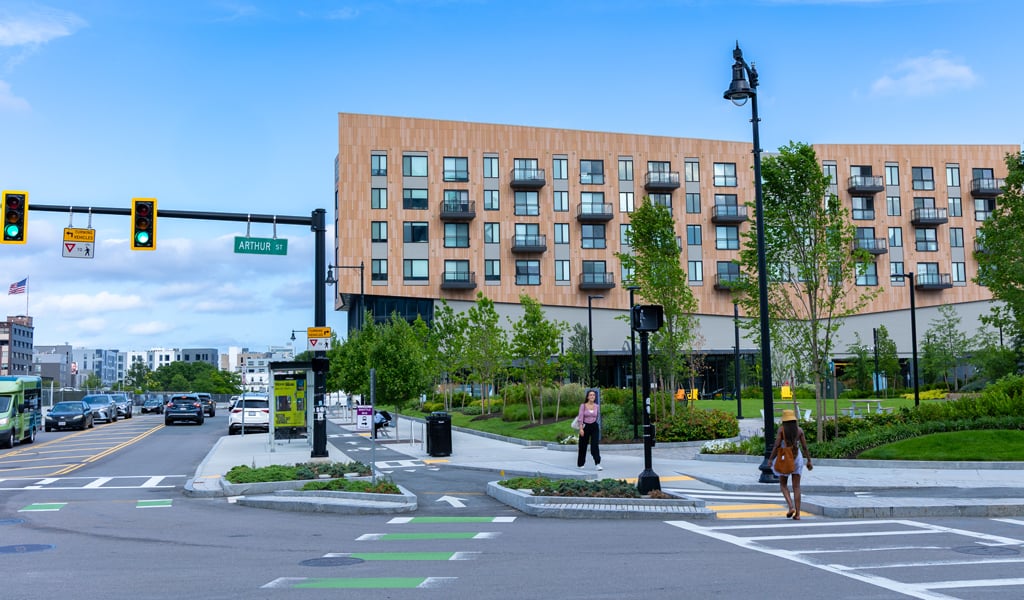 A 4-story residential building in Allston, MA, highlighting an adjacent park and busy urban streetscape. 