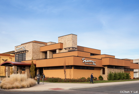 Modern Seasons 52 restaurant exterior with stone and orange facade, people walking outside