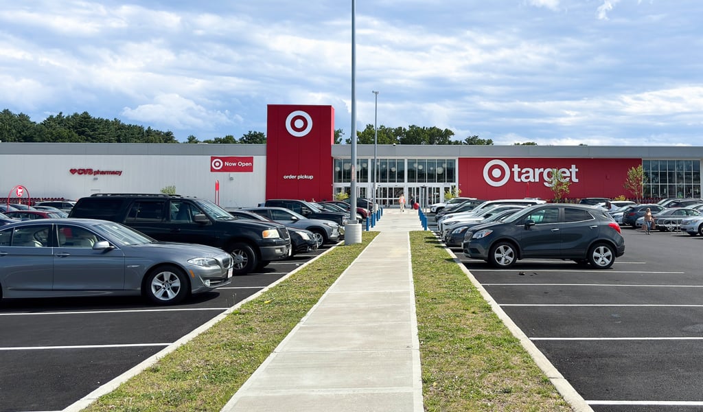 Target store with order pickup area and CVS pharmacy, surrounded by a full parking lot under a partly cloudy blue sky.