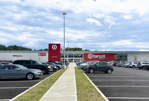 Target store with order pickup area and CVS pharmacy, surrounded by a full parking lot under a partly cloudy blue sky.