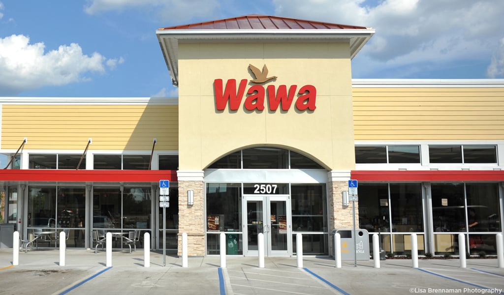 Exterior of a Wawa store under a blue sky with clouds.