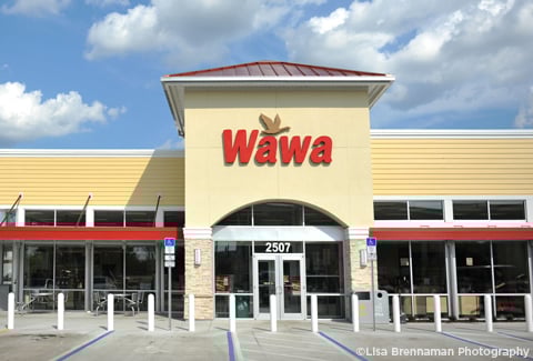 Exterior of a Wawa store under a blue sky with clouds.