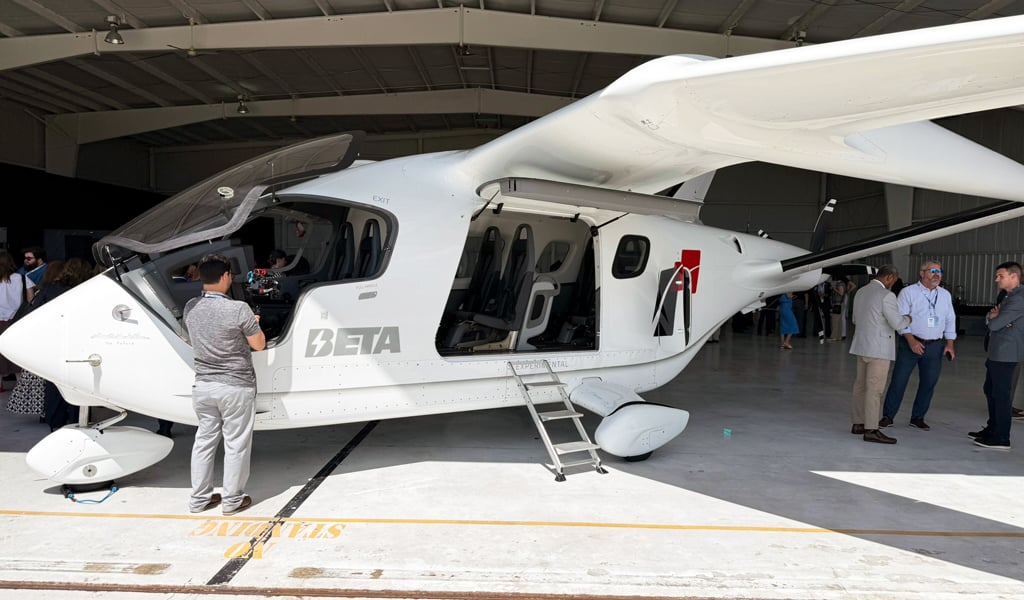 People crowd around a white eVTOL on display.
