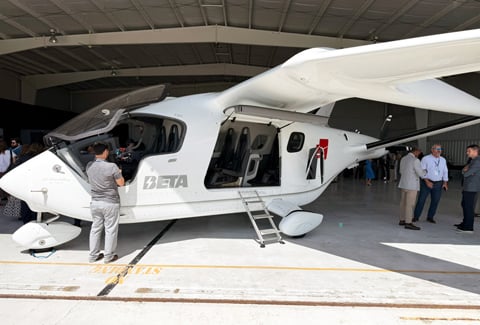 People crowd around a white eVTOL on display.