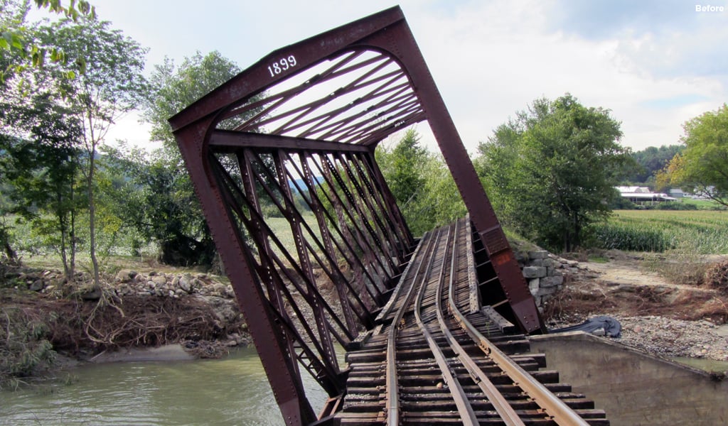 Historic covered railroad bridge tilted and collapsed into river after Hurricane Irene damage in Vermont.