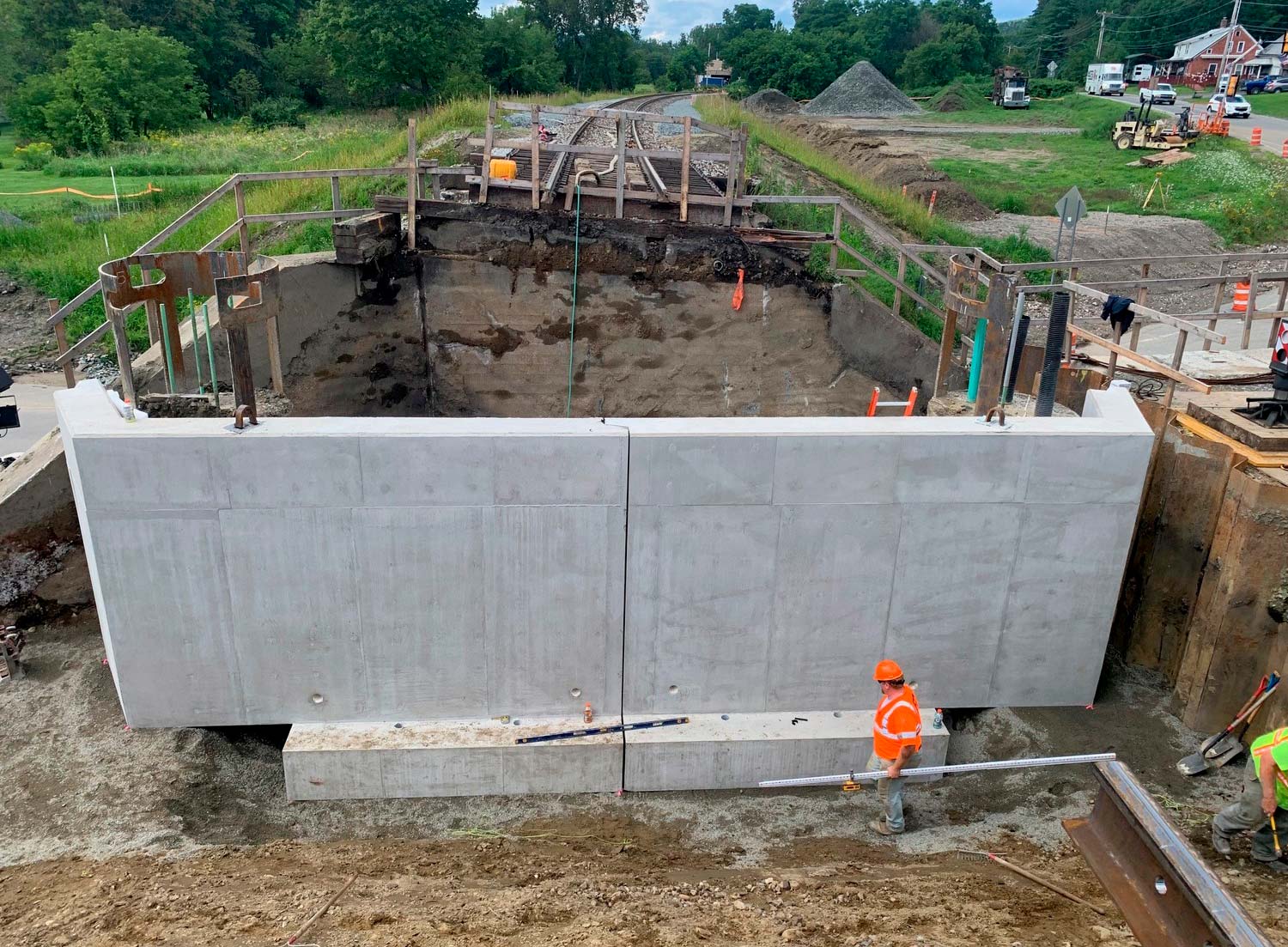 Concrete retaining wall under construction below railroad tracks. 