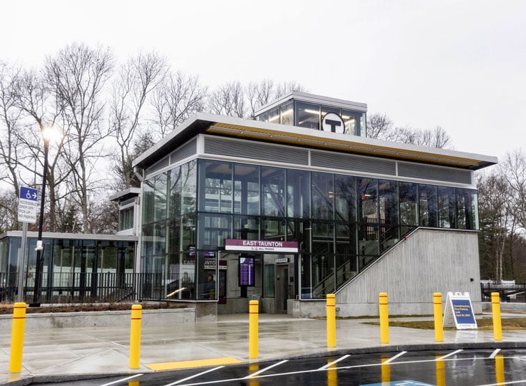 Glass and steel transit station with covered entrance and accessible walkways.