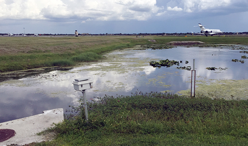 A plane sits on the runway past wetlands at Orlando Executive Airport.