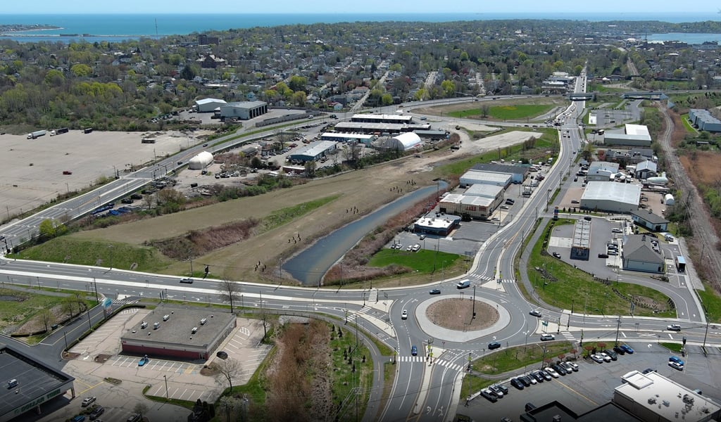 Video of a roundabout near the ocean, connecting to a bridge onramp. 