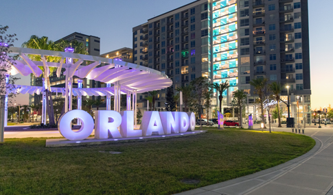 A sculpture of the word Orlando lit up at night at an outdoor park.