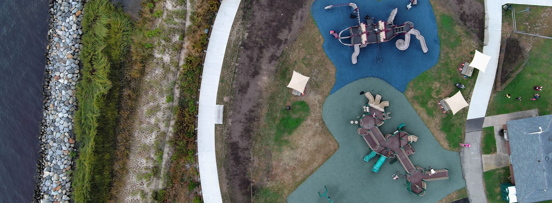 Aeriel view of playground at Shorefront Park, surrounded by green space and walking paths near the shoreline.
