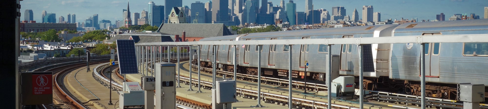 View of train and tracks with New York City skyline in the background.