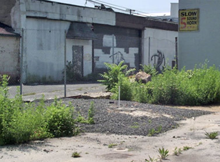 Contaminated site with buildings and weeds.