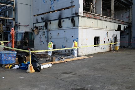 Workers oversee material removal during ongoing industrial demolition.