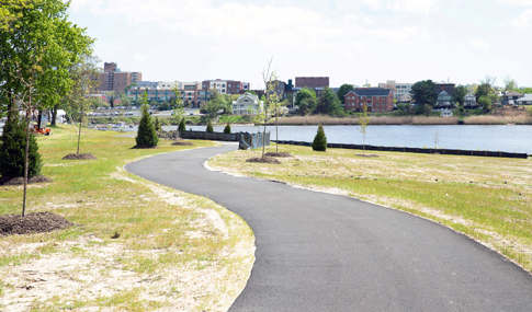 Waterfront park with boat launch and an adult and child walking along a sidewalk.