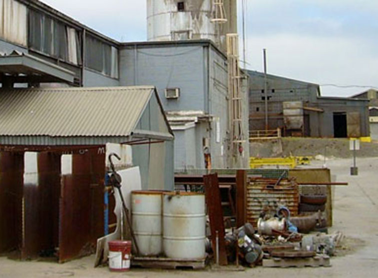 Contaminated industrial building with barrels and debris.