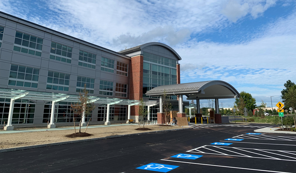 Exterior of canopied main entrance to 3-story hospital facility.