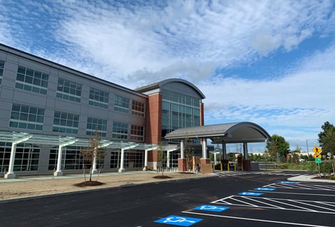 Exterior of canopied main entrance to 3-story hospital facility.