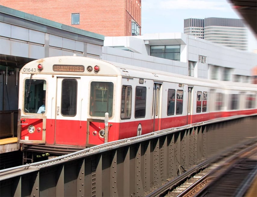 An MBTA Red Line train approaching an aboveground station.