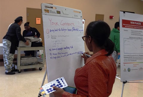 A Woman adds comments to a pad at a community forum.