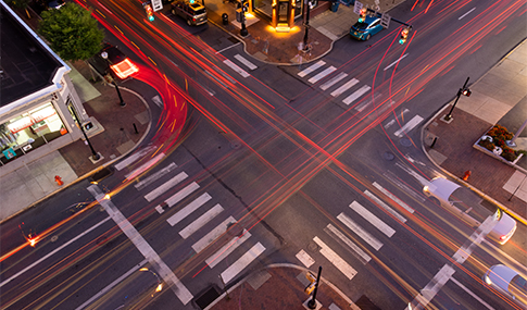 A four-way intersection on an urban street with red lines showing expected turn movements.