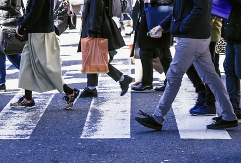 People walking in a crosswalk to cross a street.