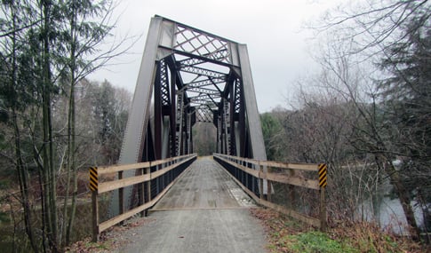 A railroad bridge converted into a multi-use trail crosses a river.
