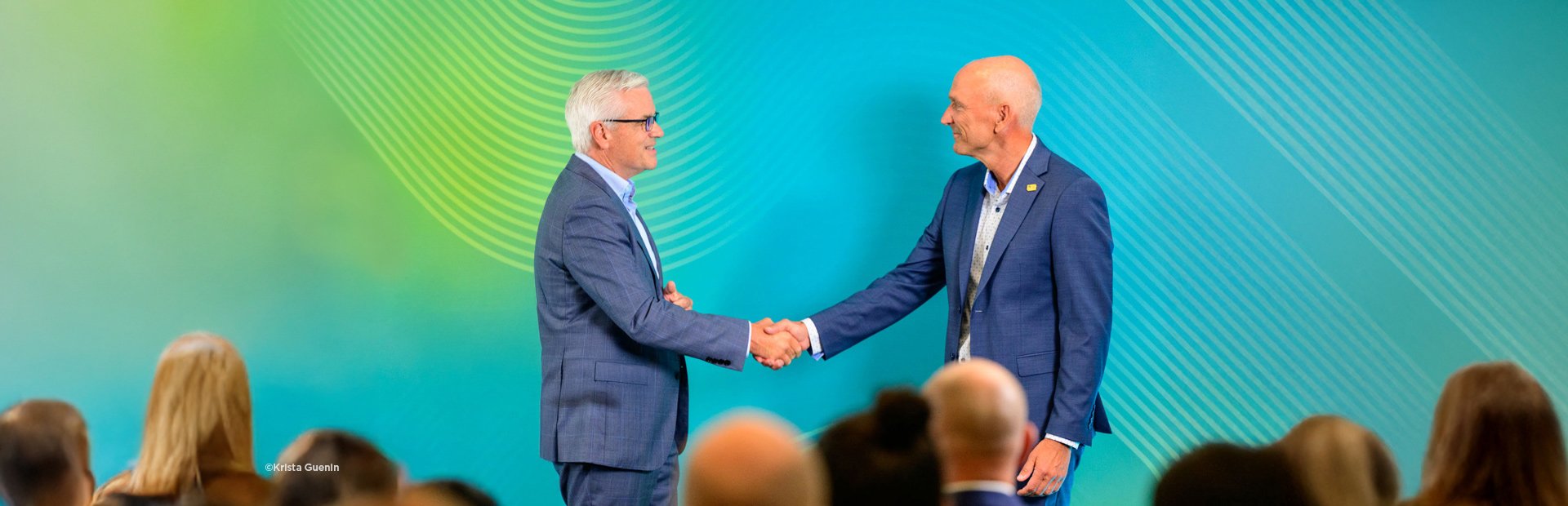 Mike Carragher & Bill Ashworth on stage in front of a colorful backdrop.