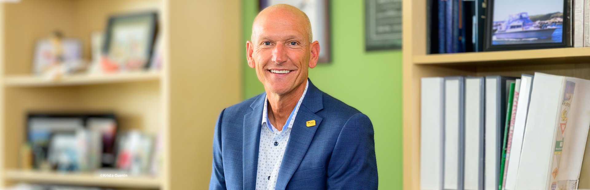 Man in blue suit sitting smiling.