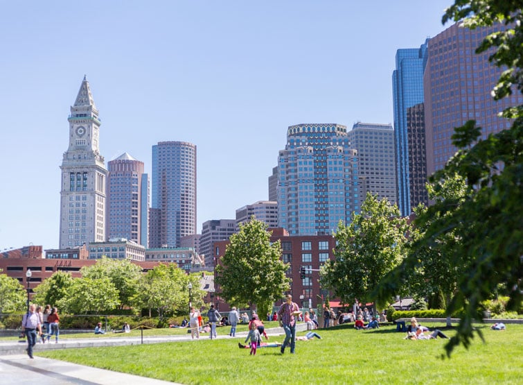 A daytime view of a city park in Boston with people relaxing on the grass.