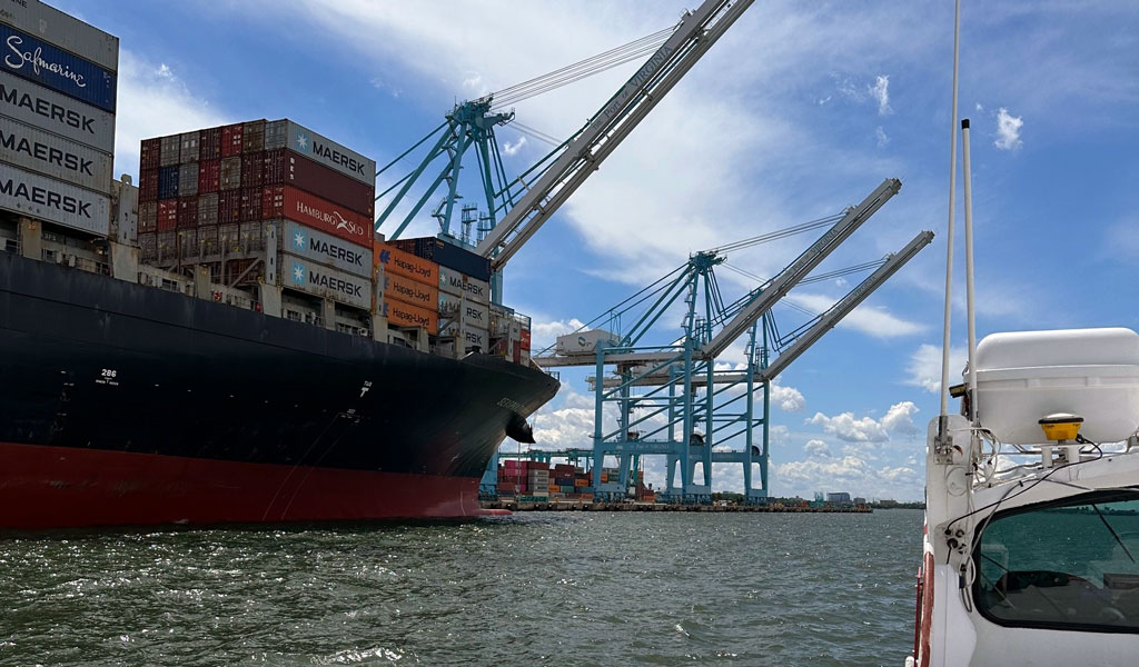 A view from a boat of a Port of Virginia container ship and cranes on a sunny day.