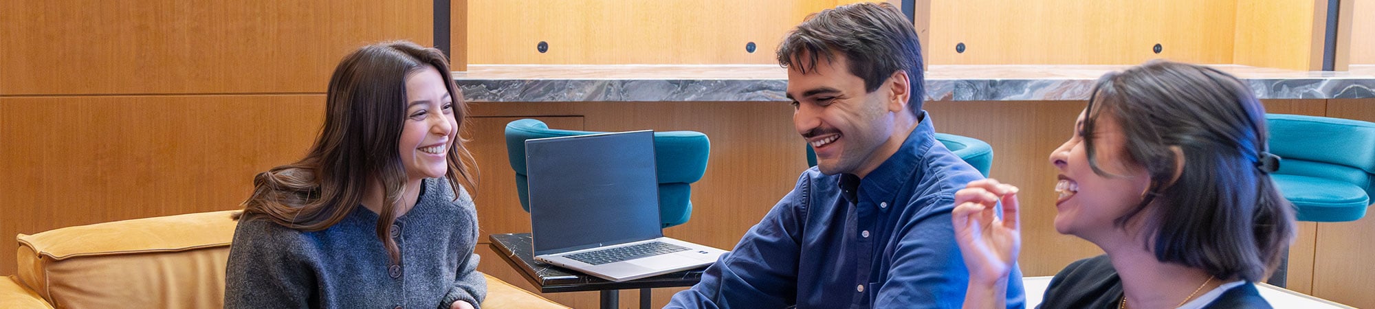 3 people sitting on a couch laughing.