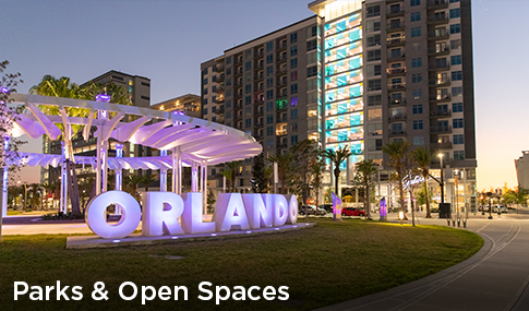 A modern urban park at night with a sculpture that spells Orlando