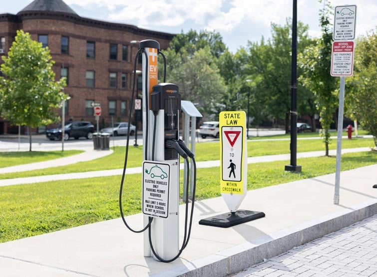 Electric vehicle charging station in front of grass and walkways.