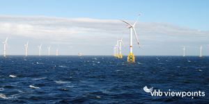 Eight wind turbines standing in the ocean.