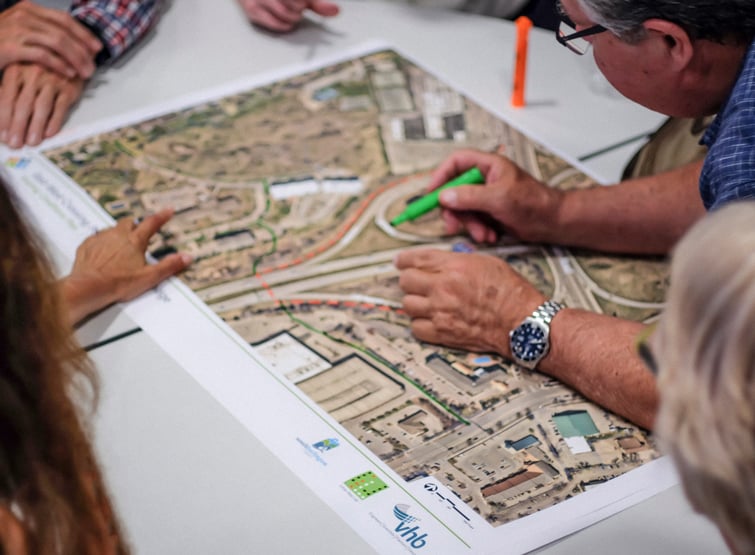 People leaning over and writing on a map on a conference table 