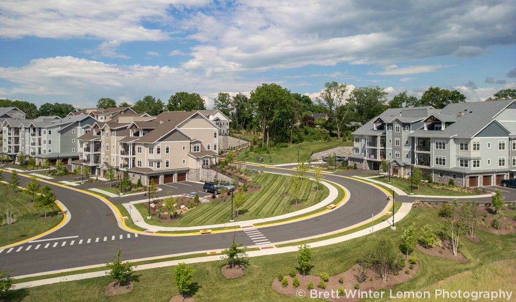 Senior living community residences set amongst landscaped roads on a partially cloudy day. 