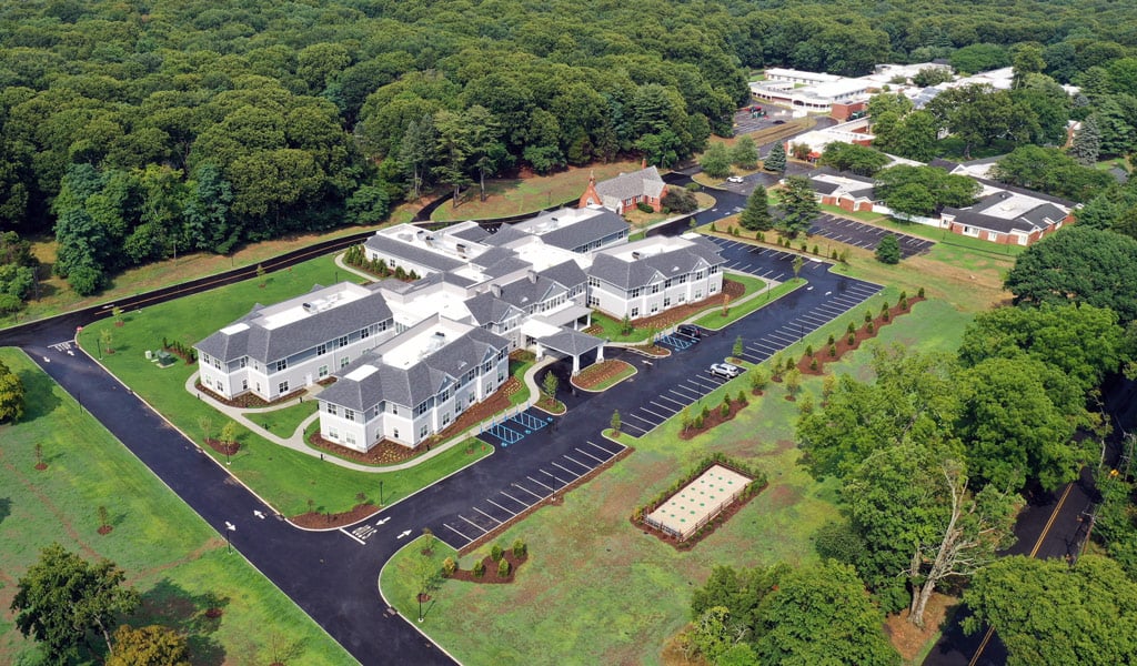 Oblique aerial photo of St. Johnland Assisted Living facility in the springtime surrounded by greenery. 