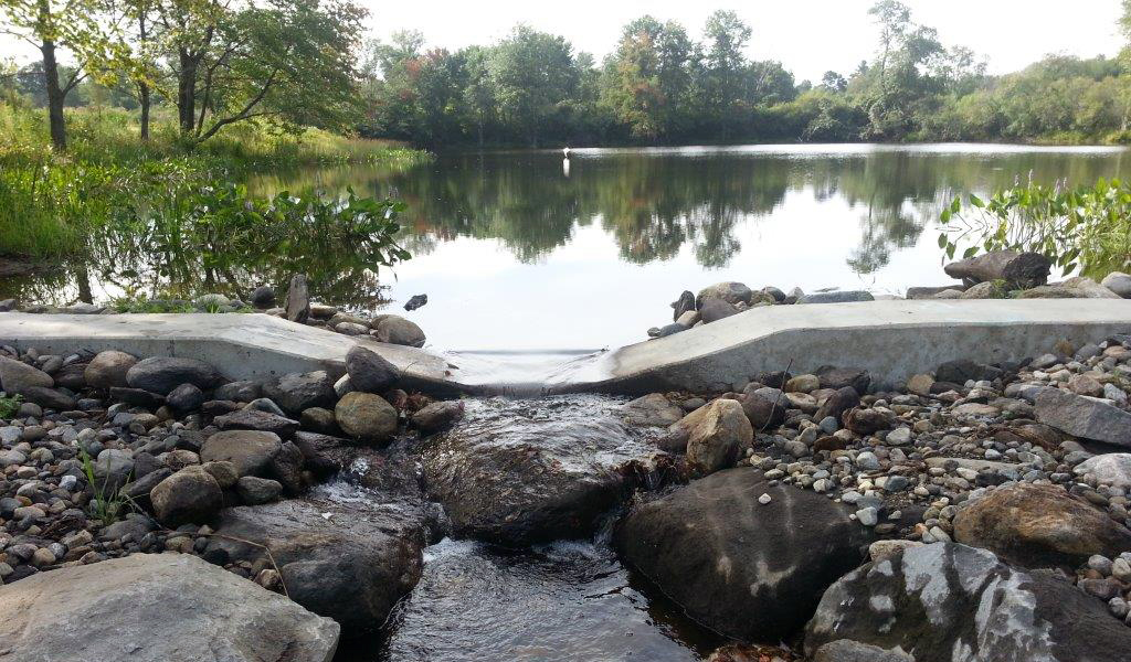 Stone spillway channel with flowing water at Owens Pond.