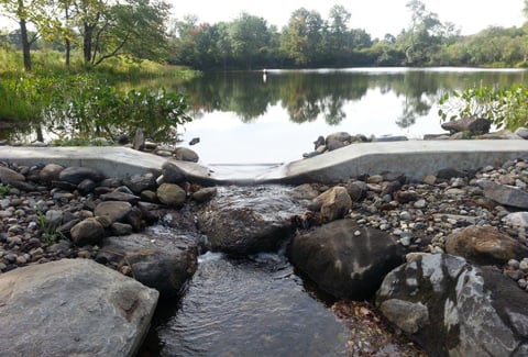 Stone spillway channel with flowing water at Owens Pond.