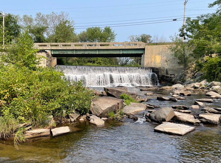 A dam spilling over into a peaceful pond.