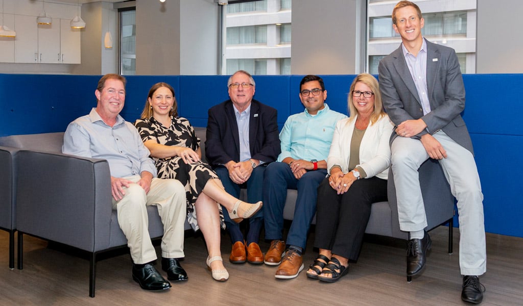 Charlotte leadership team members sit together on a gray couch.