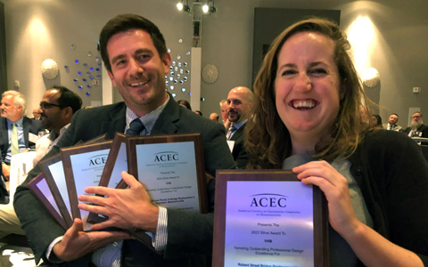 Two employees at an event dinner holding engineering awards