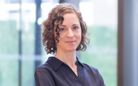 Anne-Elizabeth wearing a navy shirt in a wood-paneled room.