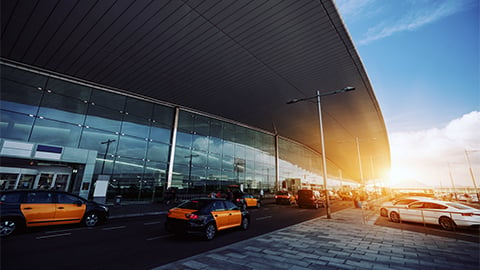 Cabstand in front of modern airport doors in Barcelona, cabrank with a lot of taxis near windowed facade of contemporary Airport terminal in Spain with road, long ceiling and parking