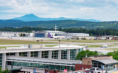 Airport buildings and runways with mountains in the background.